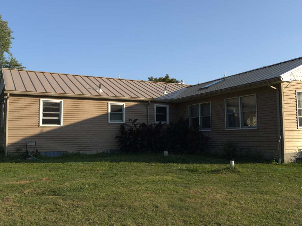 One-story house with tan metal roof and beige siding
