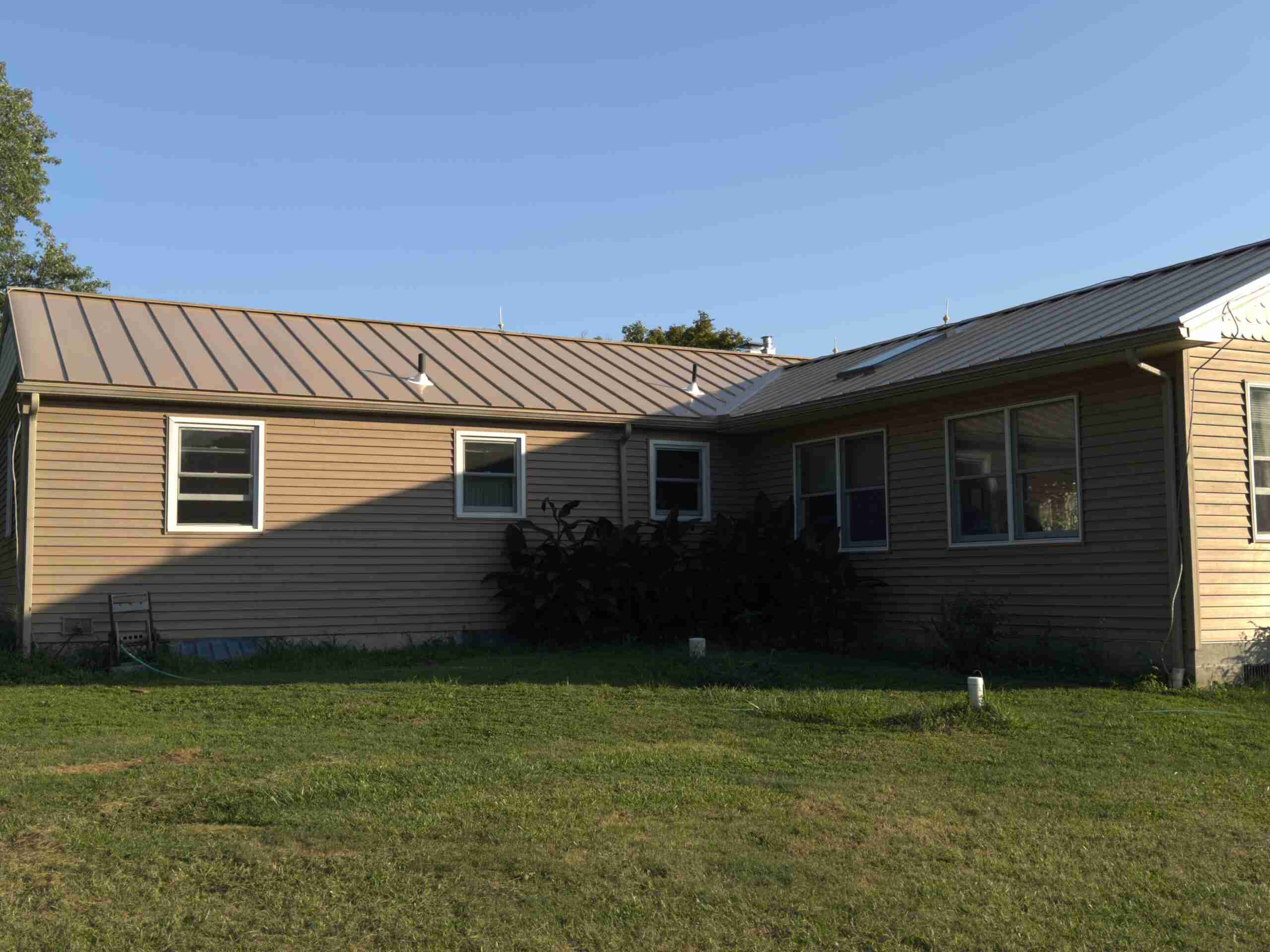 One-story house with tan metal roof and beige siding