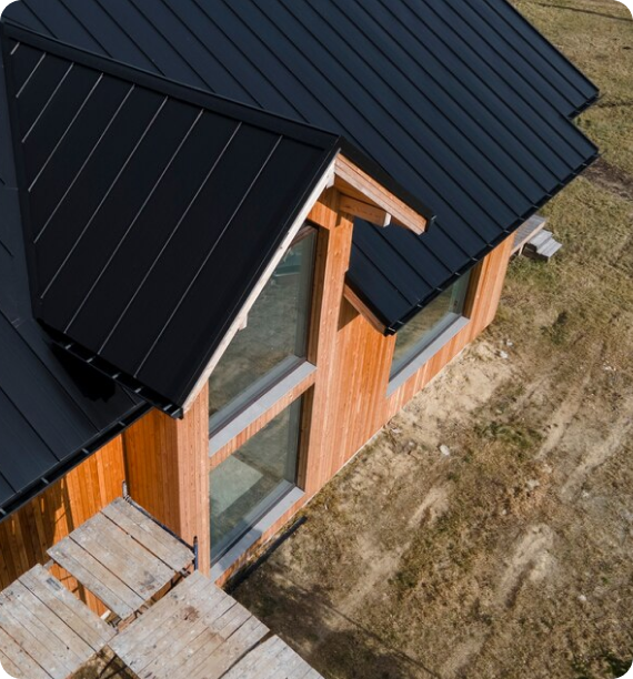 Aerial view of a wooden house with a black metal roof.