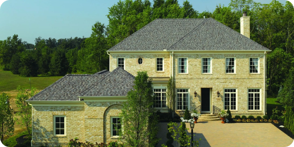 Large stone house with a gray shingle roof.