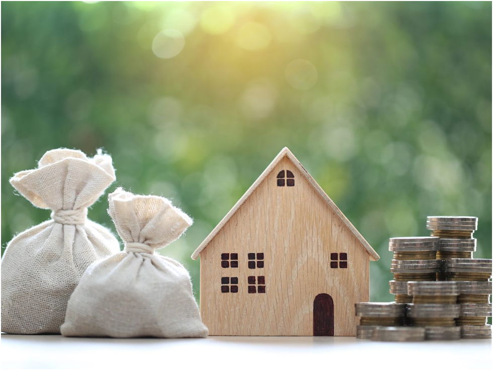 House model with coins and money bags on table
