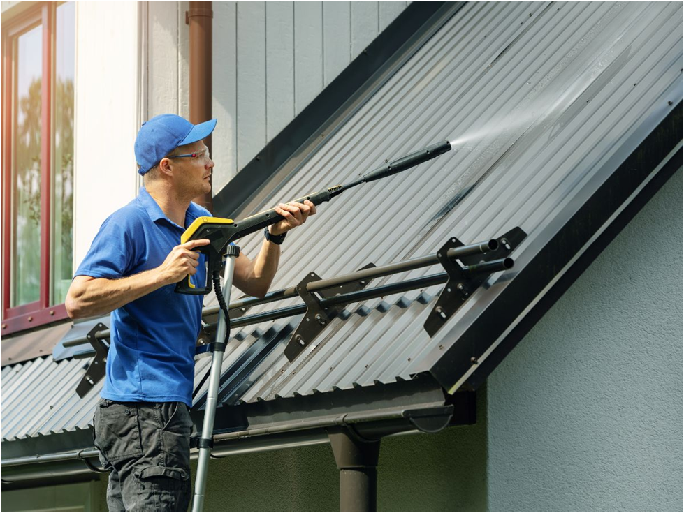 Man pressure washing a metal roof panel