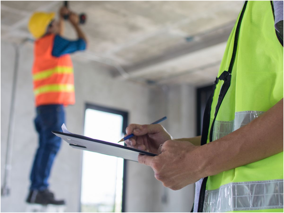 Inspector with clipboard overseeing construction work