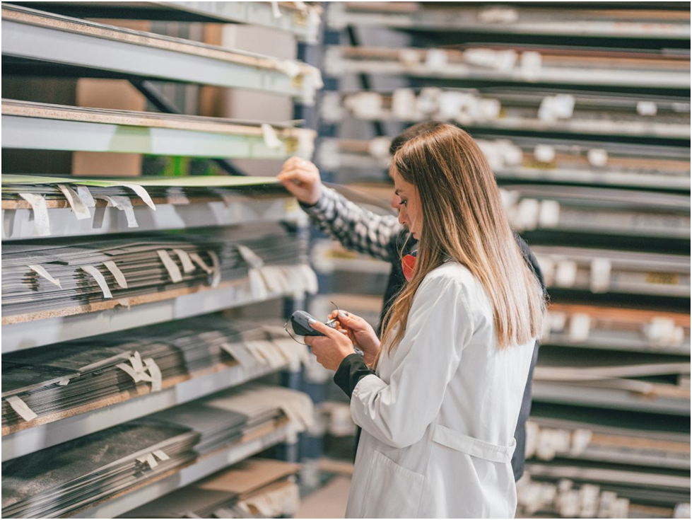 Woman inspecting sheet metal in warehouse inventory
